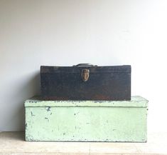 two old suitcases sitting on top of each other in front of a white wall