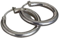 two silver colored metal hoop earrings on a white background with clippings to the side