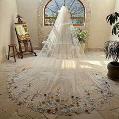 a wedding veil is draped over a bridal gown in front of an arched window