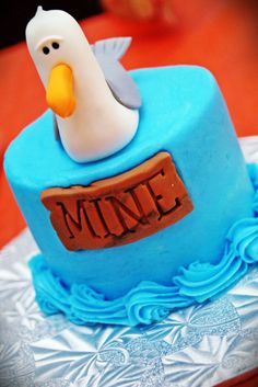 a blue cake with a white bird on top and the word mine spelled in fondant