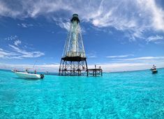 a boat is in the water near a tower on top of a pier with a sky background