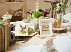 the table is set with books, vases and flowers on top of each other