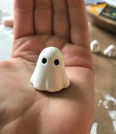 a hand holding a small white toy with black eyes and a ghost face on it