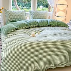 a green and white checkered comforter set on a bed in front of a window