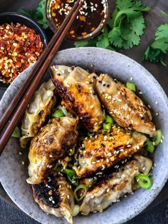 a bowl filled with chicken and noodles next to chopsticks on top of a table