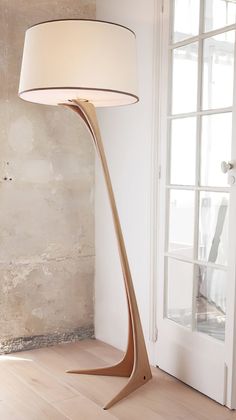 a floor lamp with a white shade on it in front of a door and window