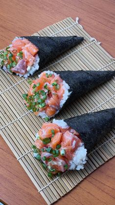 two pieces of sushi are sitting on a bamboo mat with garnishes