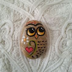 a rock with an owl painted on it's face and eyes sitting on a white blanket