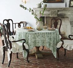 a dining room table with chairs and a potted plant on the fireplace mantel