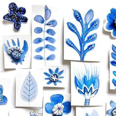 blue flowers and leaves are arranged on white cards with watercolor paper in the background