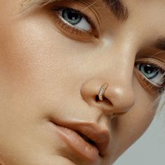 a woman with piercings on her nose looking at the camera while wearing an earring