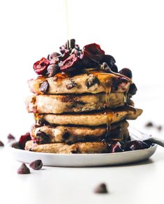 a stack of pancakes with blueberries and syrup being drizzled on top