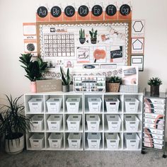 a white shelf with several bins and some plants on it next to a wall