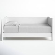 a white daybed with pillows on it in front of a white wall and floor