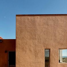 two windows on the side of a brown building with a blue sky in the background