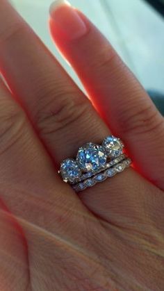 a close up of a person's hand with two rings on their wedding band