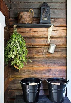 two buckets sitting on top of a table next to a potted plant in front of a wooden wall