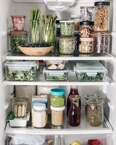 an open refrigerator filled with lots of food and containers full of vegetables, fruits and veggies