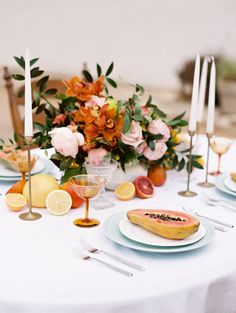 the table is set with plates, silverware, and fruit for an elegant dinner