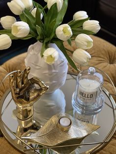 a glass table topped with a vase filled with white tulips next to a candle