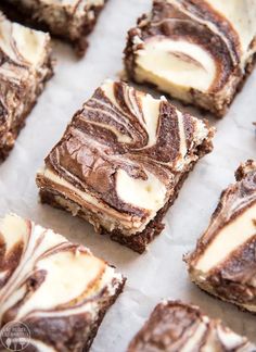 some brownies with white frosting are sitting on a piece of parchment paper and ready to be eaten