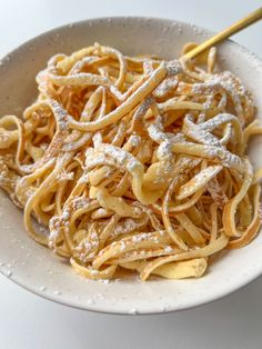 a white bowl filled with pasta covered in powdered sugar on top of a table