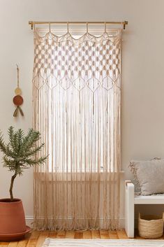 a living room with a potted plant on the floor and a curtain hanging from the window