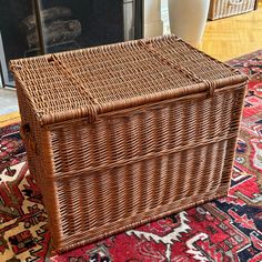 a large wicker basket sitting on top of a rug next to a fire place