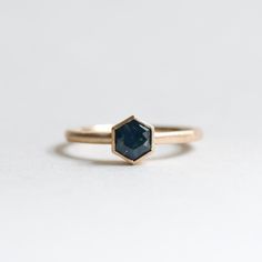 a gold ring with a faceted blue stone in the center, sitting on a white surface