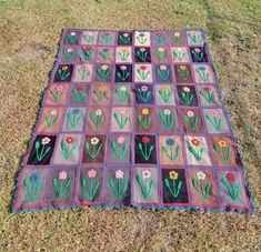 a patchwork quilt on the ground with flowers and grass in the backgroud