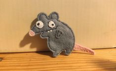 a gray mouse with big eyes is sitting on a wooden floor next to a wall