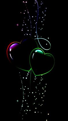 two heart shaped balloons in the dark with fireworks coming out of them and some stars