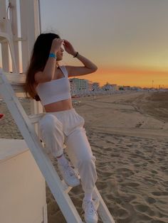 a woman sitting on top of a white ladder