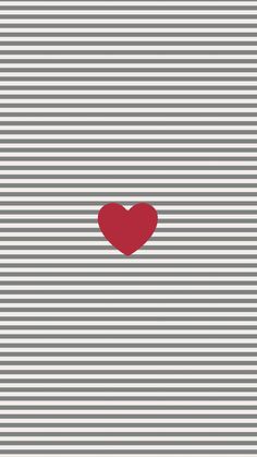 a red heart sitting on top of a gray and white striped wall