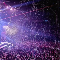 a large crowd at a concert with confetti in the air