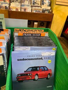 several cd's are stacked on top of each other in a green bin at a store