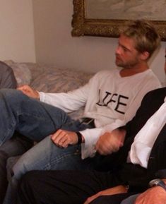 two men sitting on a couch talking to each other