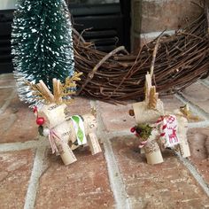 two small wooden horses sitting next to a christmas tree on a stone floor in front of a fireplace