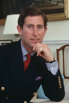 a man in a suit and tie sitting at a table with his hand on his chin