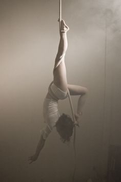 a woman hanging upside down on a pole in the air with her legs spread out