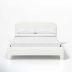 a bed with white sheets and pillows on it's headboard, in front of a wall