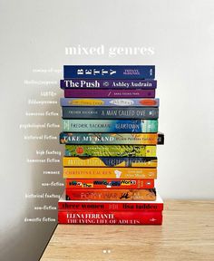 a stack of books sitting on top of a wooden table next to a white wall