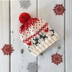 a red and white knitted hat sitting on top of snowflakes