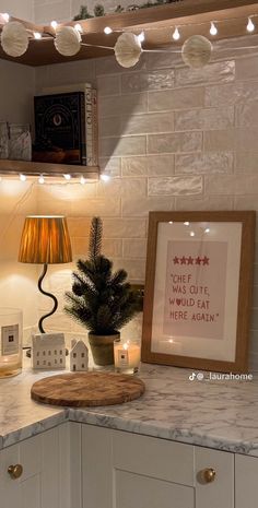 a kitchen counter topped with a potted plant next to a framed poster and lights