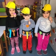 three young children wearing construction hats and holding spoons in their hands while standing next to each other