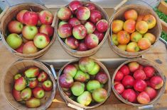 four baskets filled with apples sitting on top of a wooden table next to another basket