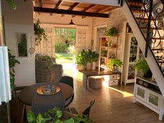 a living room filled with furniture next to a stair case and potted plant on top of a wooden table