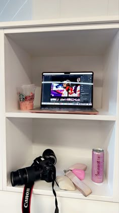 a camera is sitting on top of a book shelf next to a computer monitor and other items