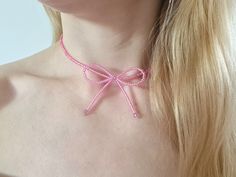 a woman wearing a pink bow tie necklace