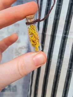 a person holding a tiny bottle filled with yellow flakes and brown string attached to it